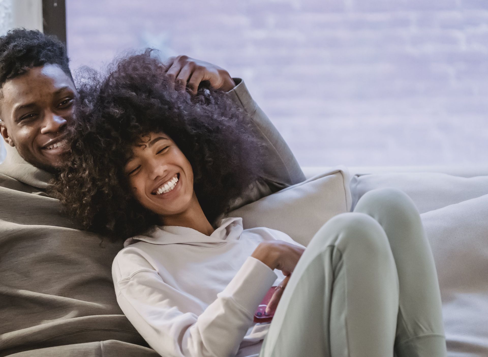 Beloved African American couple cuddling and smiling on couch